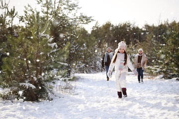 Cute little girl with her parents outdoors on winter day. Christmas vacation