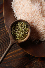 Heap of Dried Thyme Seeds in a Wooden Spoon with Allspices and Heap of Pink Himalayan Salt on a Wooden Background.