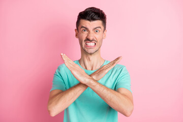 Photo of young unhappy angry aggressive displeased stressed man showing no sign isolated on pink color background