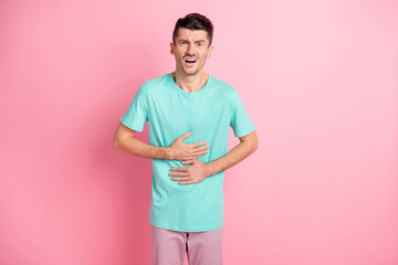 Photo of young man unhappy upset unwell suffer stomach ache ill food poison isolated over pink...