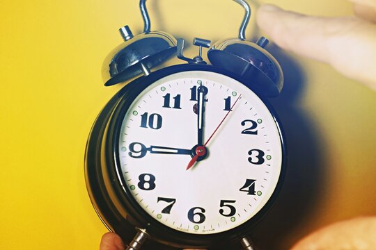 Close up of an alarm clock while ringing, hand reaching out to stop it .