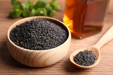 Black sesame seeds on wooden table, closeup
