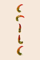 Modern concept of yummy organic unique shape peppers floating in the air and and follwing down on a beage background.