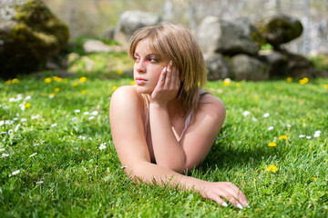Naklejka na ściany i meble Portrait of blonde woman lying on grass in park