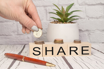 Share written on wooden dice, hand folding coins, the concept of profit and margin income