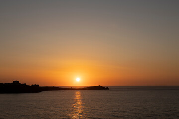 Fototapeta na wymiar Sunset over Town Head, Newquay, Cornwall with the Headland Hotel silhouetted on the headland