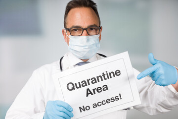 Doctor with medical face mask and medical gloves showing quarantine sign in front of a restricted...