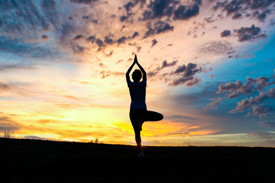 woman in a balancing pose at sunset yoga outdoors