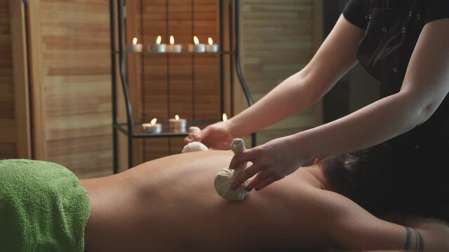 Relaxed guy lying on desk table enoying spa treatment, massage on back, came with girlfriend to get therapy by professionals.