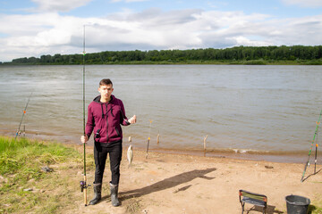 a fisherman with a fishing rod holding a fish while standing on the shore