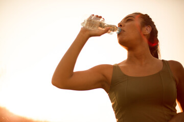 Time for break.  Sporty young woman drinking water outdoors. Focus is on woman face.