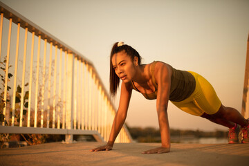 Fototapeta premium Be fit. African sportswoman doing push-ups on the bridge.