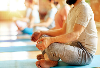 fitness, yoga and healthy lifestyle concept - group of people meditating in lotus pose at studio