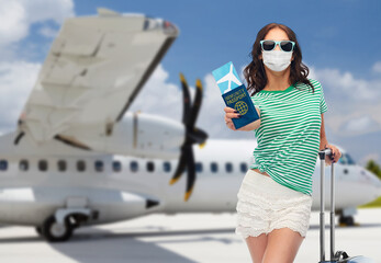 safe travel, tourism and health care concept - young woman in mask with air ticket and immunity passport over airport background