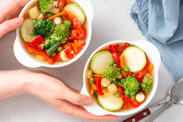 Vegetable soup with broccoli, romanesco, pepper, zucchini, and peas in a white bowl. Vegan soup,...