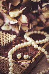 White pearl necklace and earrings on an antique book, vintage style, vertical, closeup