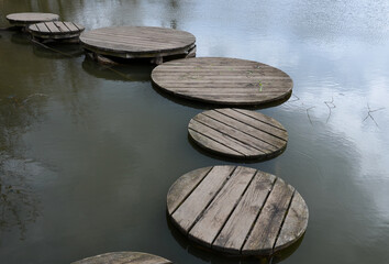floating walkway made of wood planks. narrow curved leads above the lake water. has no railings....