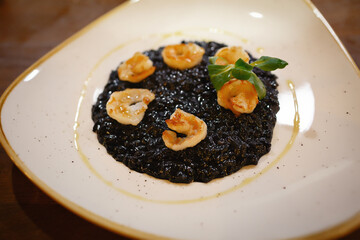 Black caviar with fried shrimps on a large white plate in a restaurant