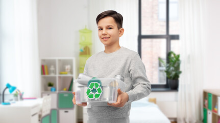 metal recycling, waste sorting and sustainability concept - smiling boy in striped t-shirt holding plastic box with tin cans over home room on background