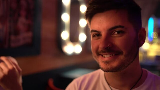 Chico joven guapo sonriendo a camara en un bar con tematica circense