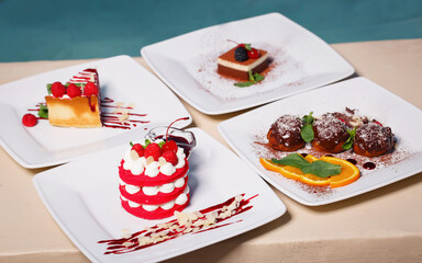 Composition of four sweet desserts in plates on the background of the pool on the street. Cheesecake with raspberries, millefeuille with cherries, profiteroles with chocolate