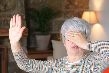 Embarrassed senior woman blocking vision with hand