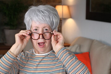Impressed senior woman holding eyeglasses