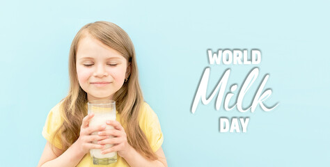 World milk day. Cute little girl with her eyes closed drinks white milk from transparent glass on blue background. Baby child with cup of milk. Banner