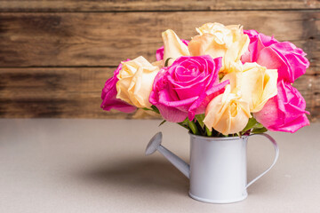 Bouquet of fresh multicolored roses in a watering can