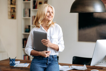 Portrait of a charming elegant caucasian blonde woman, standing in an office near her workplace,...