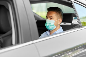safety, health care and people concept - young man or male passenger wearing face protective medical mask for protection from virus disease in car