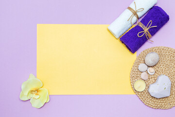 Scented candles, towel, soap and orchid flowers on a yellow and purple background.