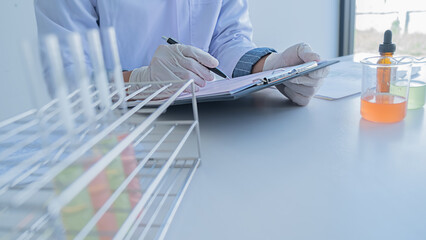 Medical or scientific researcher or man doctor looking at a test tube of clear solution in a laboratory