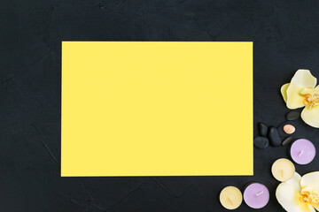 Candles, orchid flowers and pebbles on a black and yellow background.
