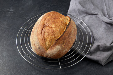 Naklejka premium food, baking and cooking concept - homemade craft bread on metallic grid stand on table