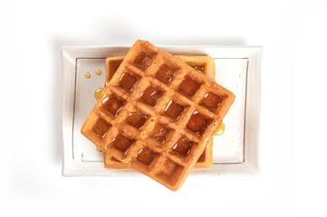 Waffles with honey on white plate isolated on white background.