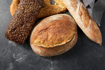 food, baking and cooking concept - close up of different bread on kitchen towel