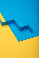 Abstract minimal paper background. Blue zig zag cut out paper stripe on blue and yellow paper background.