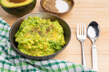 Guacamole freshly cooked and served in a bowl on a wooden table. Mashed avocado. Top view. Mexican foods and healthy vegan food concept