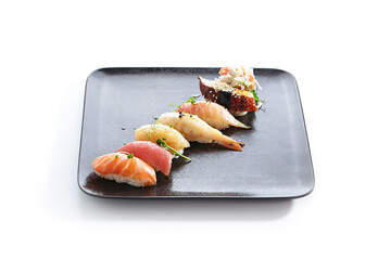 Japanese Nigiri Sushi Set - Sushi with Rice and Various Seafood. Salmon, Tuna, Sea Scallop and other seafood fish. Nigiri Sushi row on black slate platter. Isolated on white background.