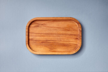 Empty wooden tray on textured dark blue table. Rectangular wooden dish top view. Kitchen minimal...