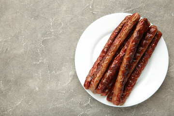 Roasted sausage on plate on grey background