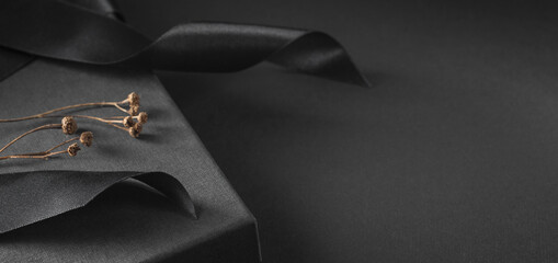 Black gift box, decorated with a bow and dry twigs.	
