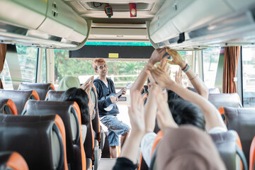 a busker using an ukulele musical instrument and bus passengers sing and clap their hands while traveling