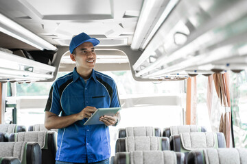 close up of a male bus crew member uses a digital tablet while checking shelves inside the bus