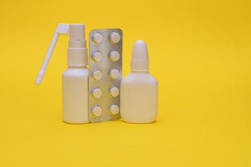 Nasal spray, throat spray, and blister-packed tablets. The concept of treating colds and flu. On a yellow background.