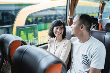 a man and woman chatting and laughing while sitting on the bus while traveling