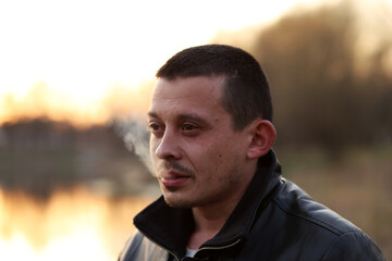 Portrait of a man smoking cigarette on a background of sunset