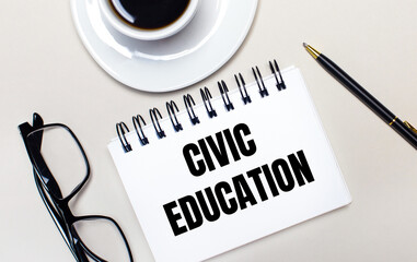 Glasses, a white cup of coffee, a white notebook with the words CIVIC EDUCATION and a ballpoint pen lie on a light background. Flat lay. View from above.