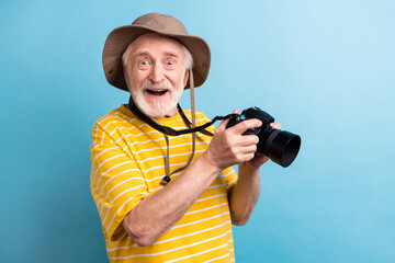 Photo of happy amazed cheerful old man hold camera good mood take picture isolated on blue color background